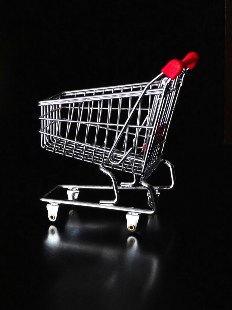 pexels-photo-264547-264547 A shiny miniature shopping cart with red handles on a black reflective surface.