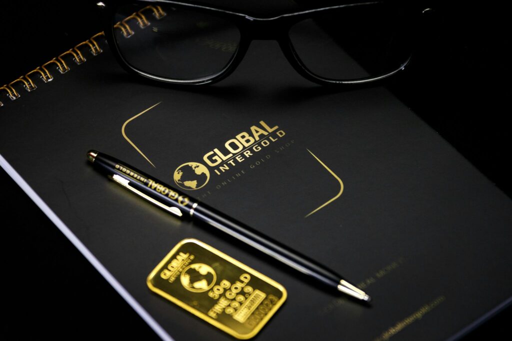 An elegant setup with a notebook, pen, and gold bar, embodying luxury and style.