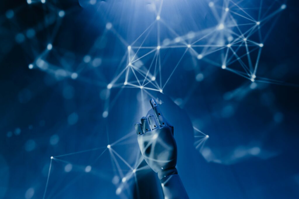 A human hand with tattoos reaching out to a robotic hand on a white background.